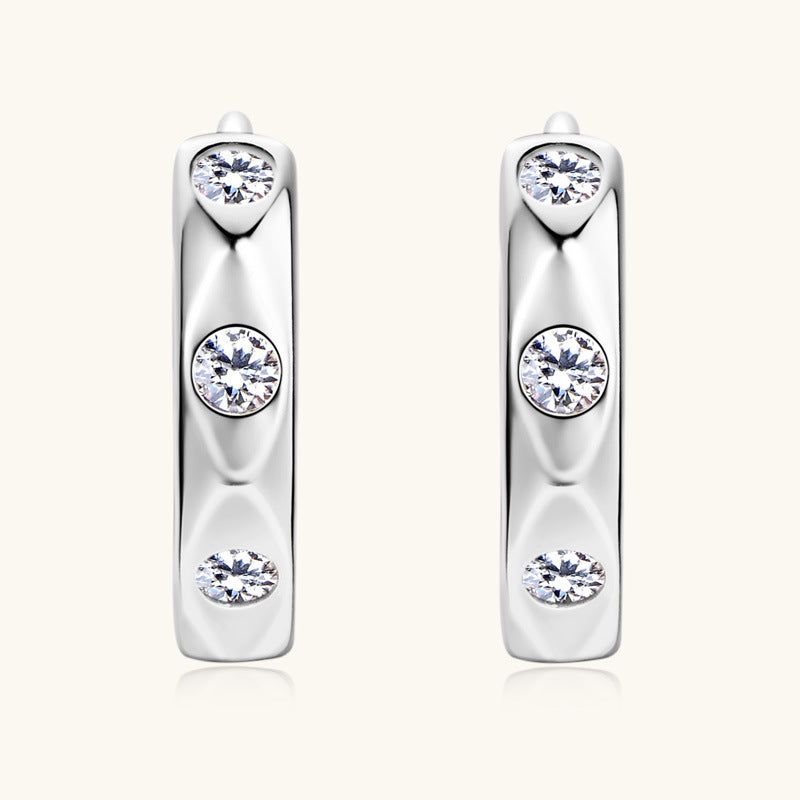 Angled shot showing moissanite sparkle in sterling silver huggie earrings