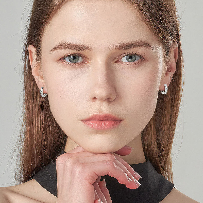 Woman wearing sterling silver moissanite huggie earrings lifestyle shot