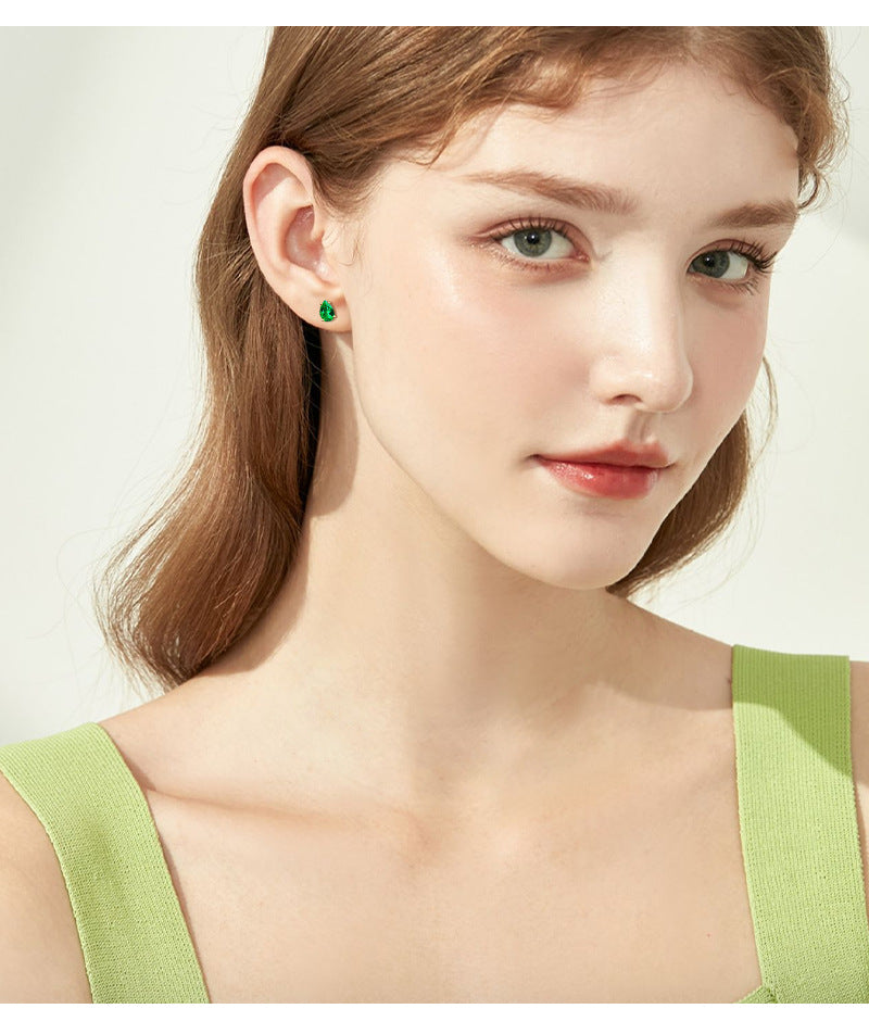 Close-up of emerald stone in silver hoop earrings