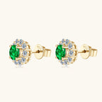Silver earring with star motif and green emerald on white background