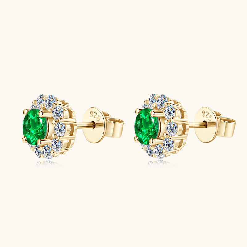 Silver earring with star motif and green emerald on white background