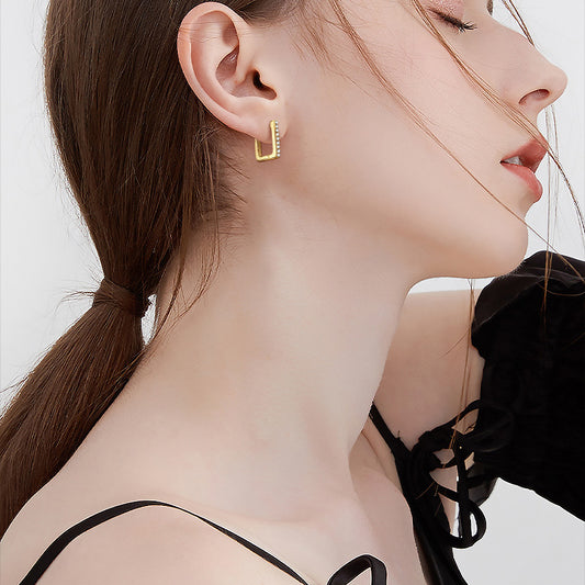 Close up detail of 14K gold huggie earrings showing secure hinge mechanism