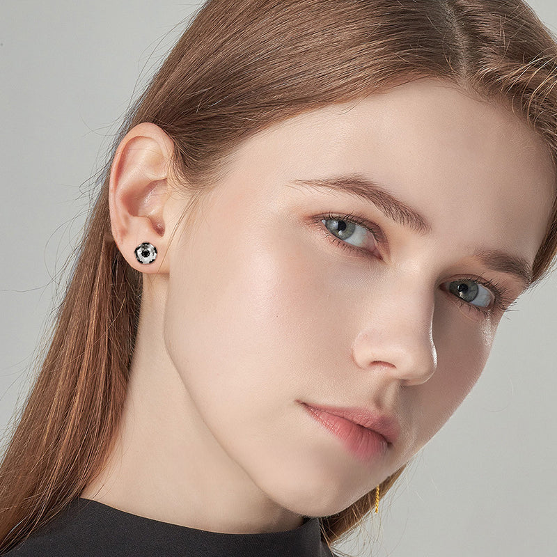 Sterling silver stud earring with black gem on plain backdrop