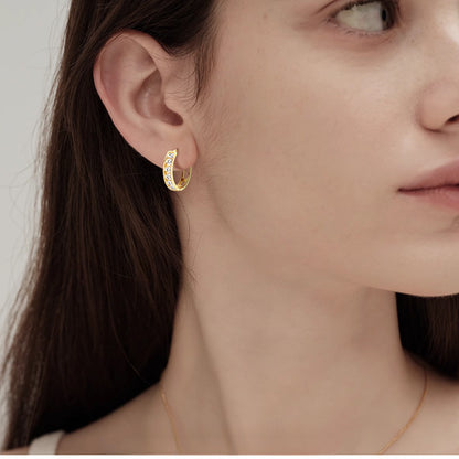 Side view of small gold huggie hoops showing thickness