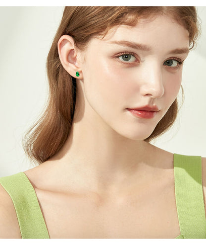 Side view of luxury emerald drop hoop earrings in gold