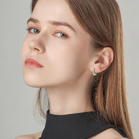Close-up detail of moissanite stones in sterling silver huggie earrings
