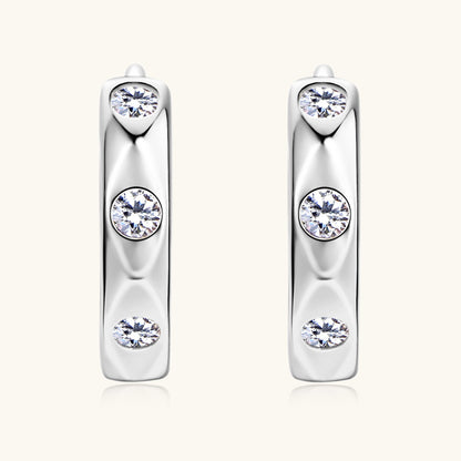 Angled shot showing moissanite sparkle in sterling silver huggie earrings