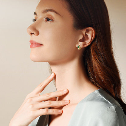 Side angle of gold huggie earrings displaying secure clasp mechanism and emerald settings