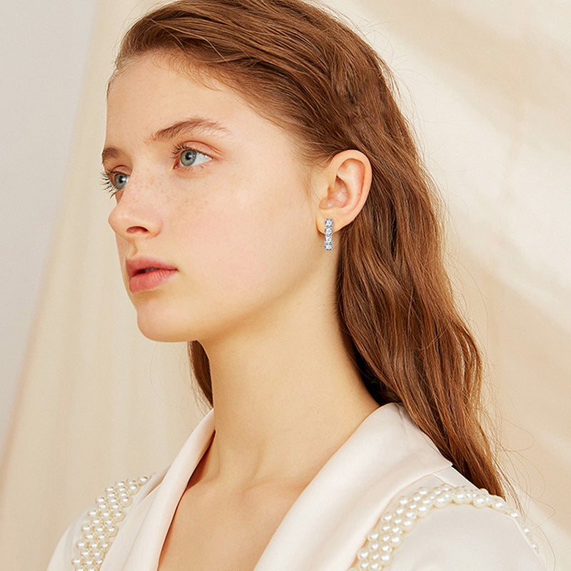 Woman wearing small sterling silver huggie hoop earrings with moissanite stones daily